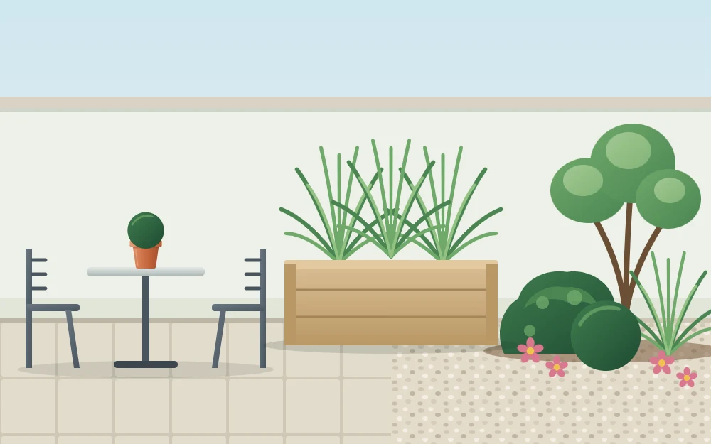 Side view of a patio separated from a planting area by a low wooden planter box of grasses, with paving on one side and gravel on the other