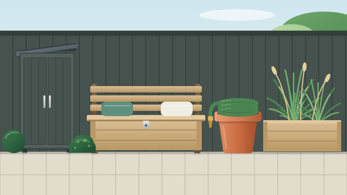 Tidy garden corner with a wooden storage bench, a slim dark cupboard matching the fence, a hose coiled in a pot and a planter of grasses